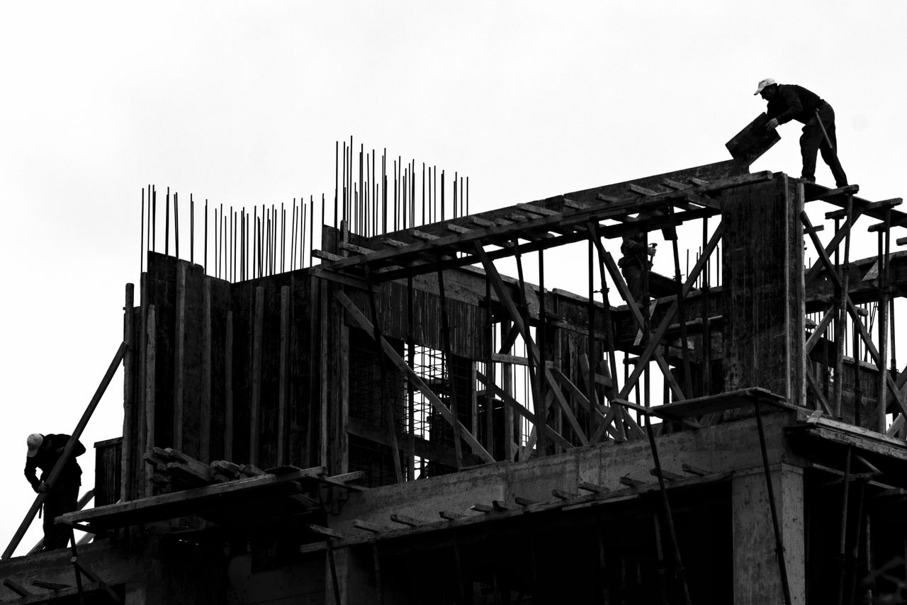 Services-01 Black and white silhouette of workers on a building site. Dramatic and industrial.